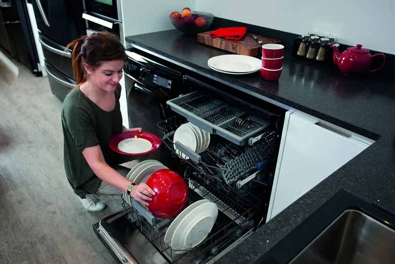 A homeowner loading plates into an open dishwasher
